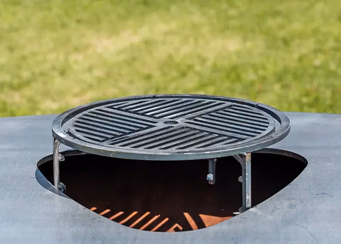 Detail des runden Gussrosts über der Feuerschale eines modernen Außengrills.
