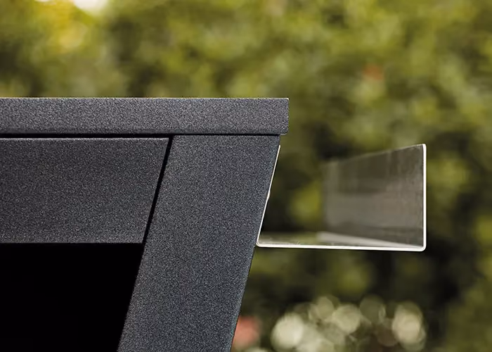 Nahaufnahme einer in einen modernen Außengrill mit schwarzem Metallrahmen integrierten seitlichen Stahlauflage.