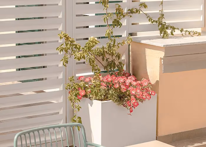 Separatori per esterni Modularte: divisori frangivista bianchi in metallo per hotel e stabilimenti balneari, completi di vasi per piante e arredo outdoor.