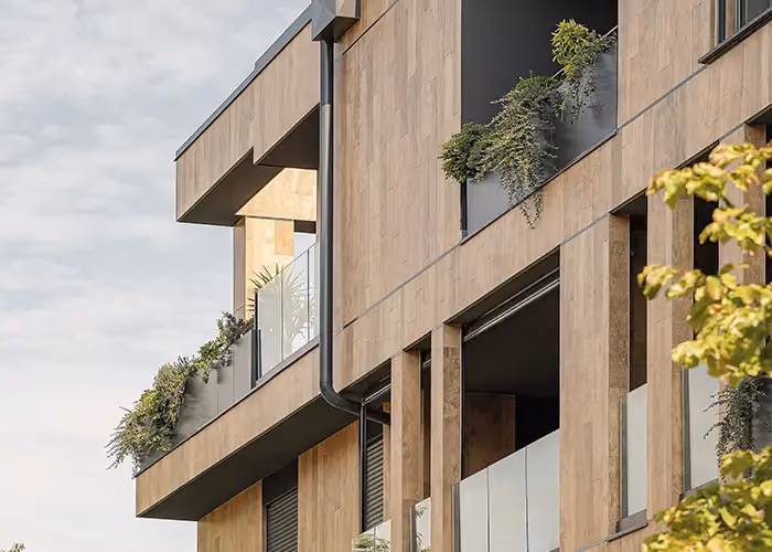 Facciata di edificio moderno con balconi dotati di fioriere parapetto in metallo scuro e vegetazione decorativa ricadente.