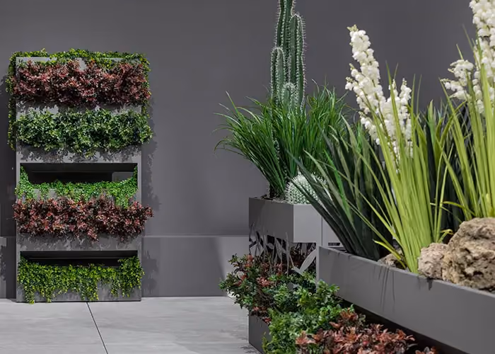 Komposition aus modernen Pflanzgefäßen und einem modularen vertikalen Garten mit Zierbepflanzung in einem zeitgenössischen Ausstellungsraum.