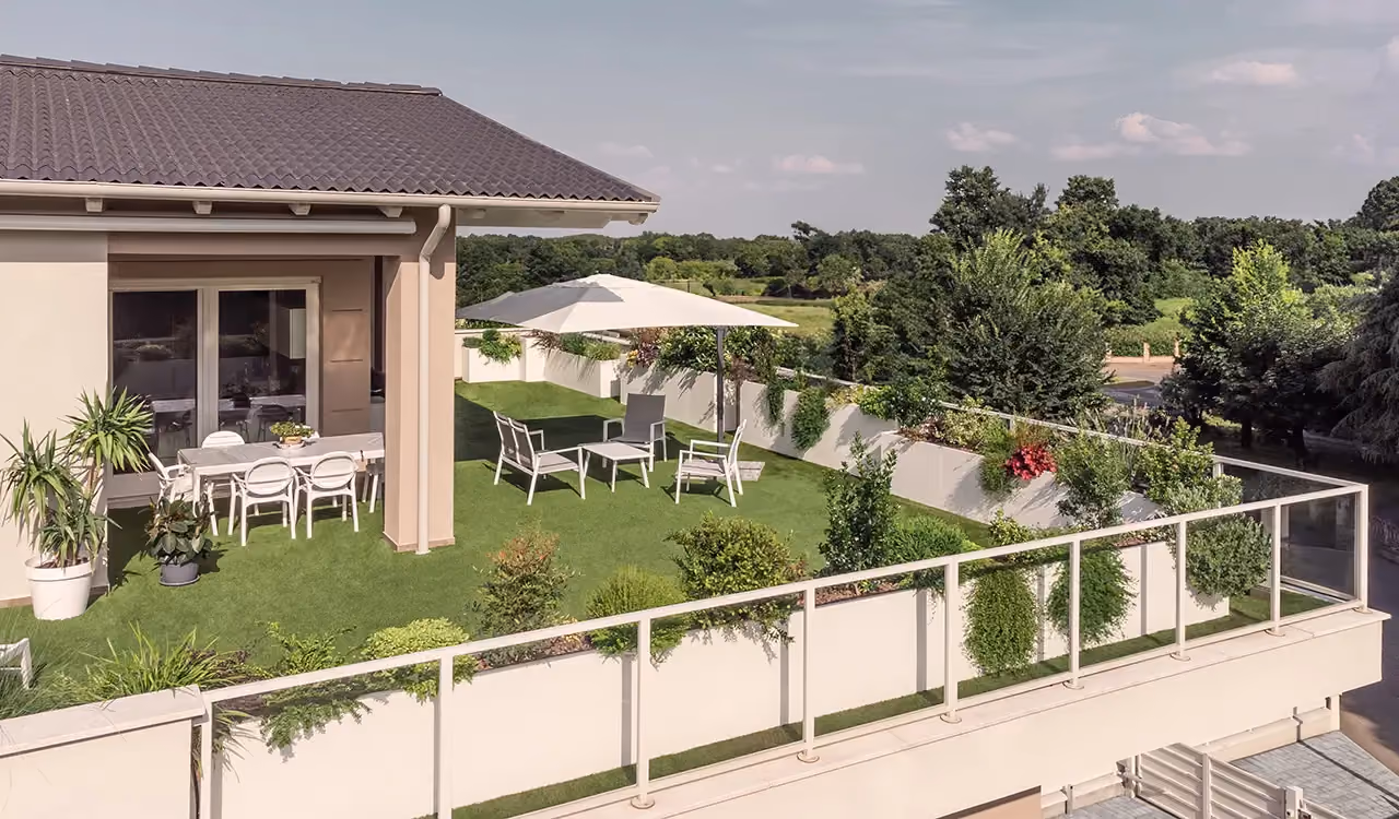 Giardino con fioriere modulari lungo il perimetro di un terrazzo, davanti a una villa