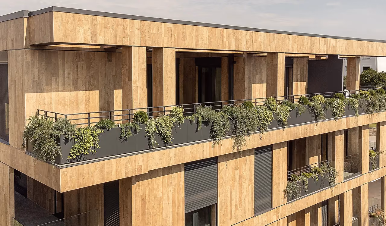 Schräge Luftaufnahme einer langen Penthouse-Terrasse, umgeben von durchgehenden dunklen Randpflanzgefäßen voller Kletterpflanzen und Efeu.
