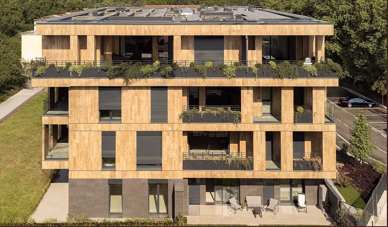 Fassade eines modernen Designer-Wohnhauses mit Verkleidung in Holzoptik, mit Balkonen und Terrassen mit integrierten Pflanzgefäßen und überhängenden Pflanzen über mehrere Ebenen.