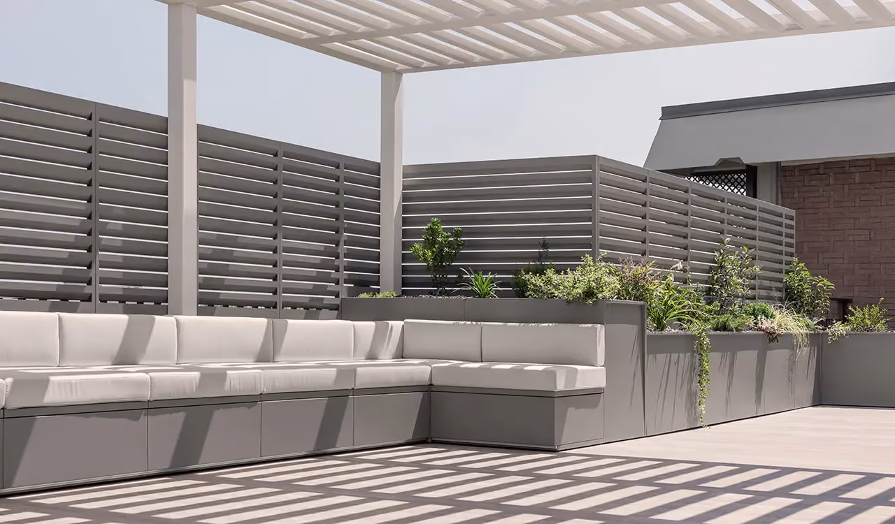 Terrazza coperta da pergola con divani grigi e fioriere alte a schermatura